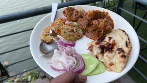 naan served with aloo dum, chaat and some salad in floatel with water in the background.
