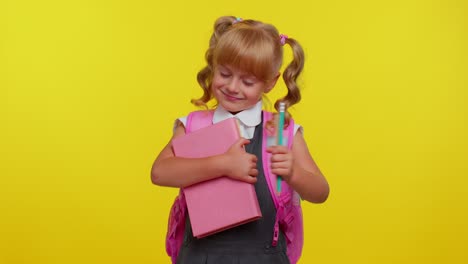 Cheerful-funny-schoolgirl-kid-with-books-dressed-in-uniform-wears-backpack-smiling-looking-at-camera