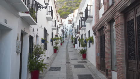 calle estrecha vacía en la ciudad española de mijas con casas de fachada blanca