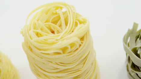 Three-roll-of-tagliatelle-and-green-tagliatelle-pasta-on-white-background