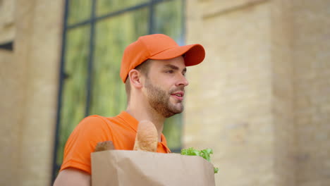 Courier-using-mobile-phone-for-searching-address.-Man-delivering-food-in-bag.