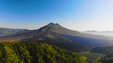 drone flying over trees to visualize mount batur , an active vulcano in bali, indonesia