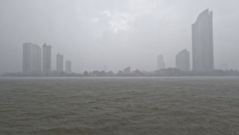 heavy rain or rainstorm over chao phraya river in bangkok with high buildings silhouette in background, thailand