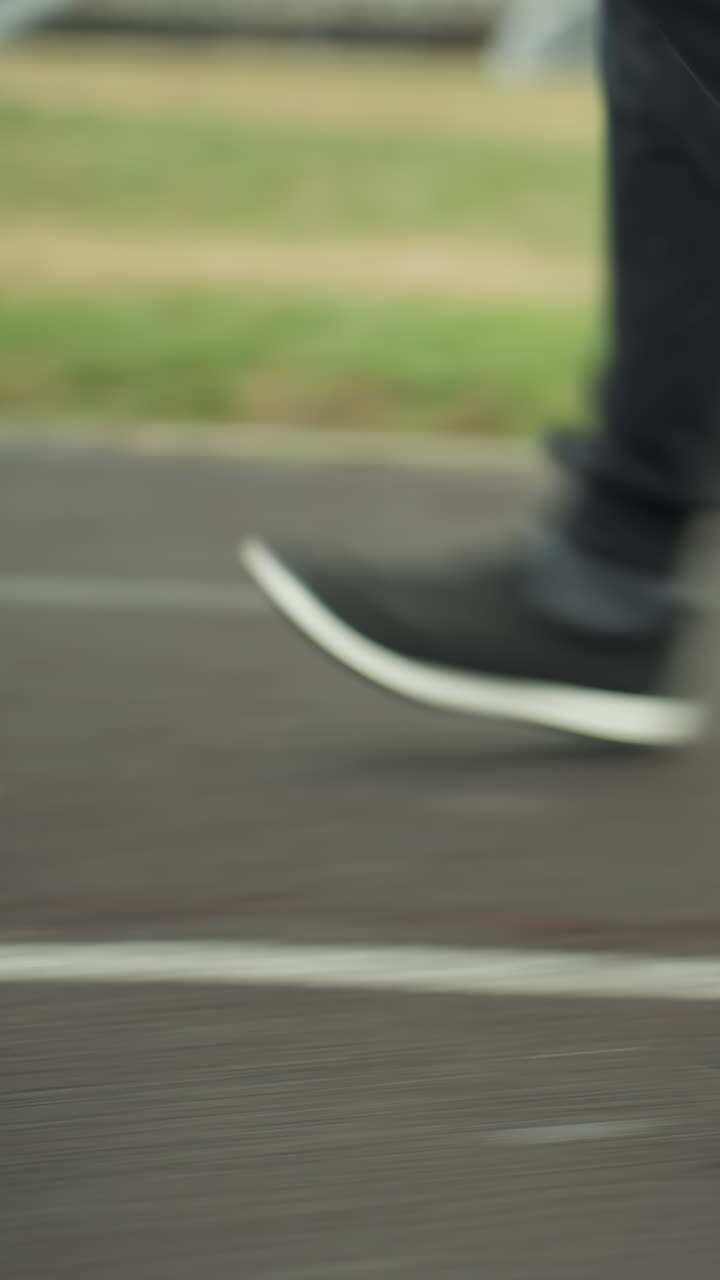 Close-up leg view of three people wearing joggers and sneakers, jogging in sync on a track close to a grassy field