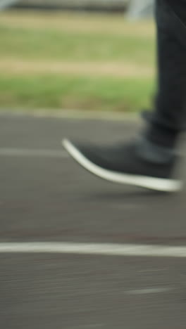 close-up leg view of three people wearing joggers and sneakers, jogging in sync on a track close to a grassy field