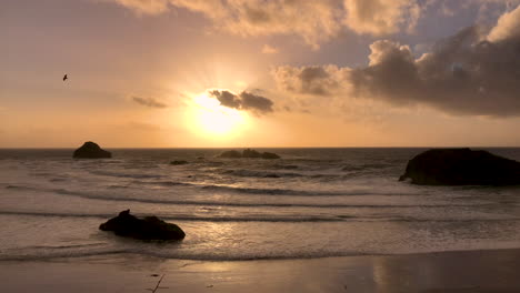 hermosa puesta de sol y las olas rodando en la playa de bandon en la costa de oregón