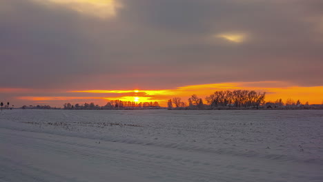 Zeitraffer-Goldener-Sonnenaufgang-Im-Offenen-Feld-Im-Winter,-Ländliches-Riga,-Lettland