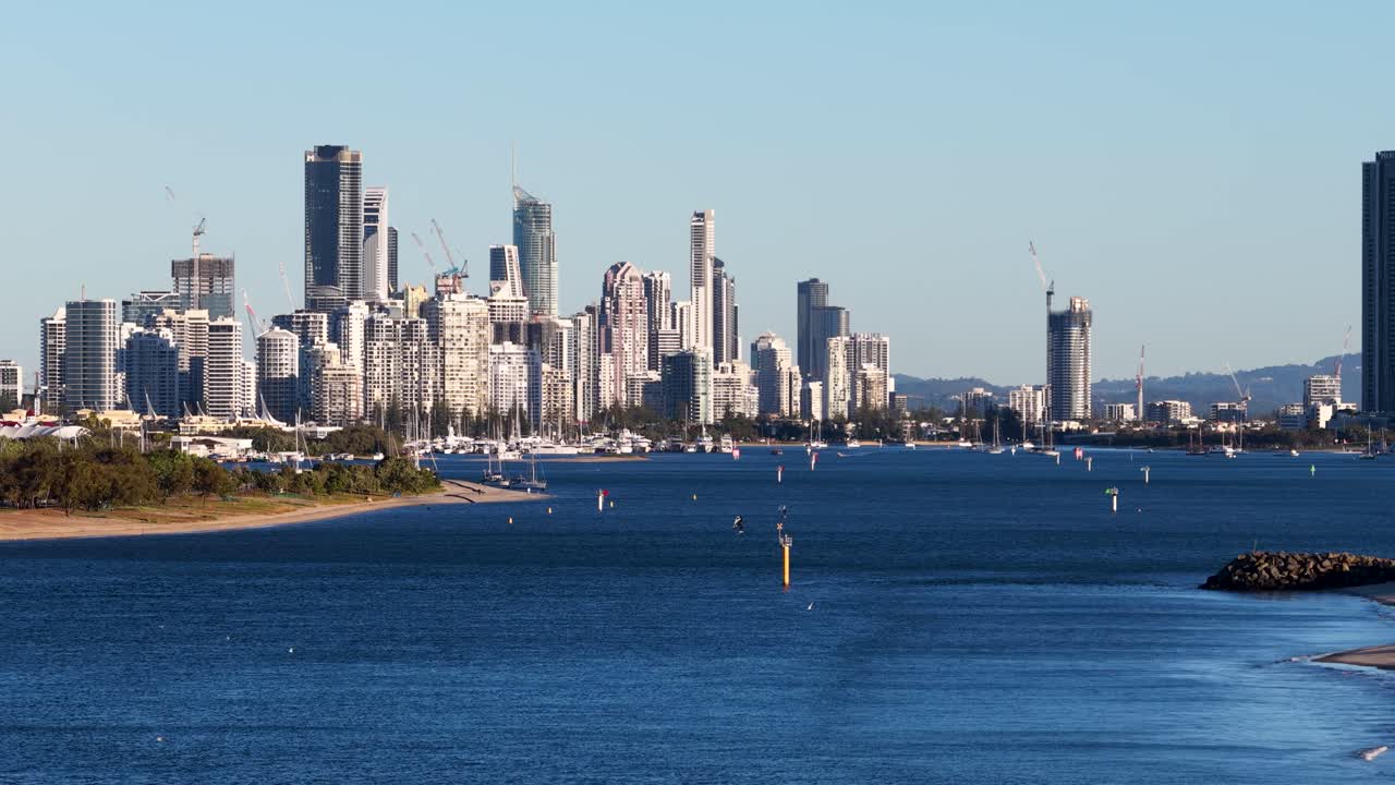 Drone captures Gold Coast skyline with vibrant sunset lighting, showcasing urban landscape and serene waterway
