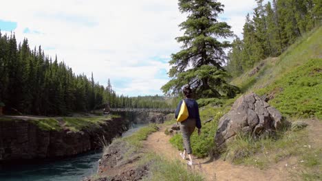 Indian-woman-walks-along-the-Miles-Canyon-nature-trail,-long-shot