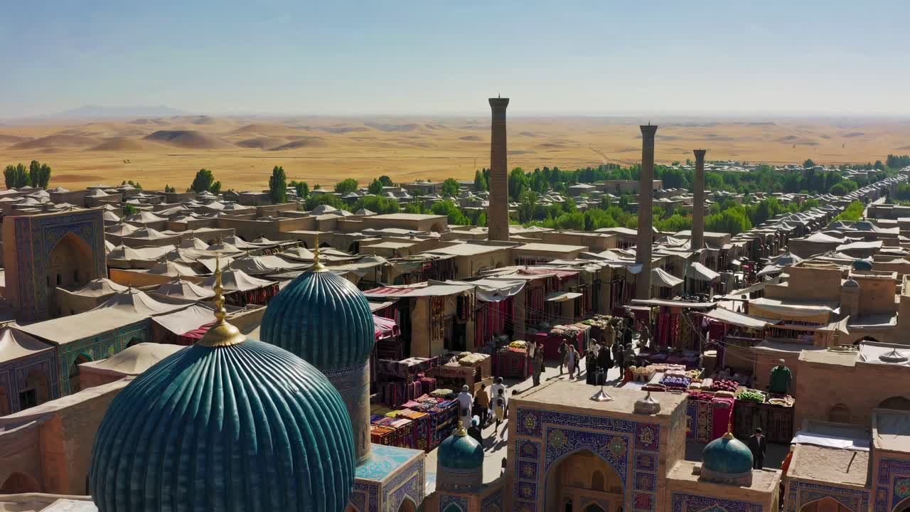 High-angle video shot of a bustling market with colorful textiles, domed rooftops, and distant