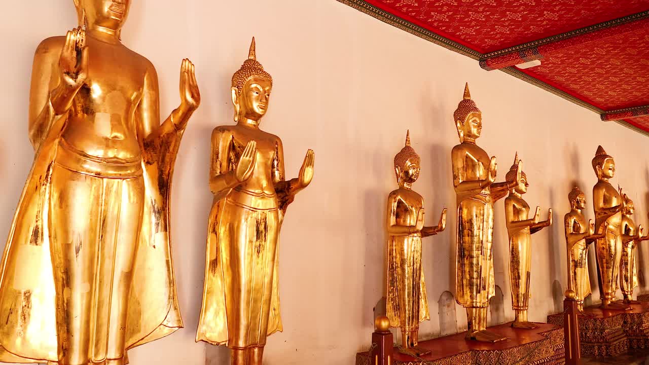una fila de estatuas de buda de oro en wat pho