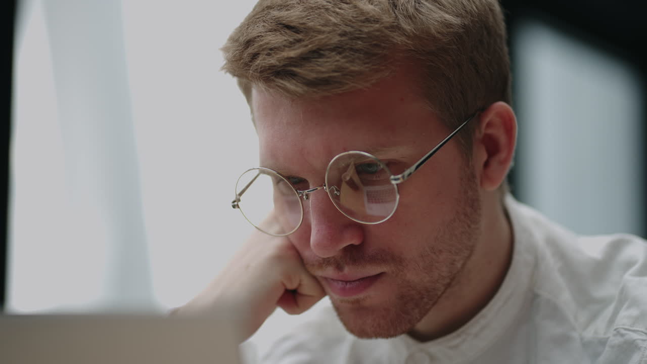 hombre caucásico inteligente con gafas está leyendo información en la pantalla de la computadora portátil vista de cerca de la cara