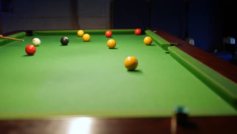 a man potting a yellow ball on a pool table in to the center pocket