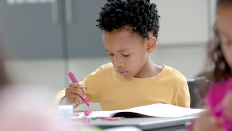 in school, young african american boy focusing on drawing in classroom