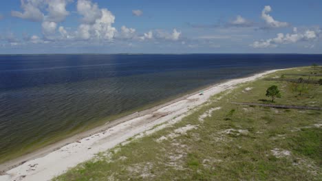 Luftflug-Entlang-Eines-Abgelegenen-Strandes-Im-Golf-Von-Mexiko,-An-Dem-Jemand-Etwas-Schatten-Unter-Einem-Sonnenschirm-Genießt