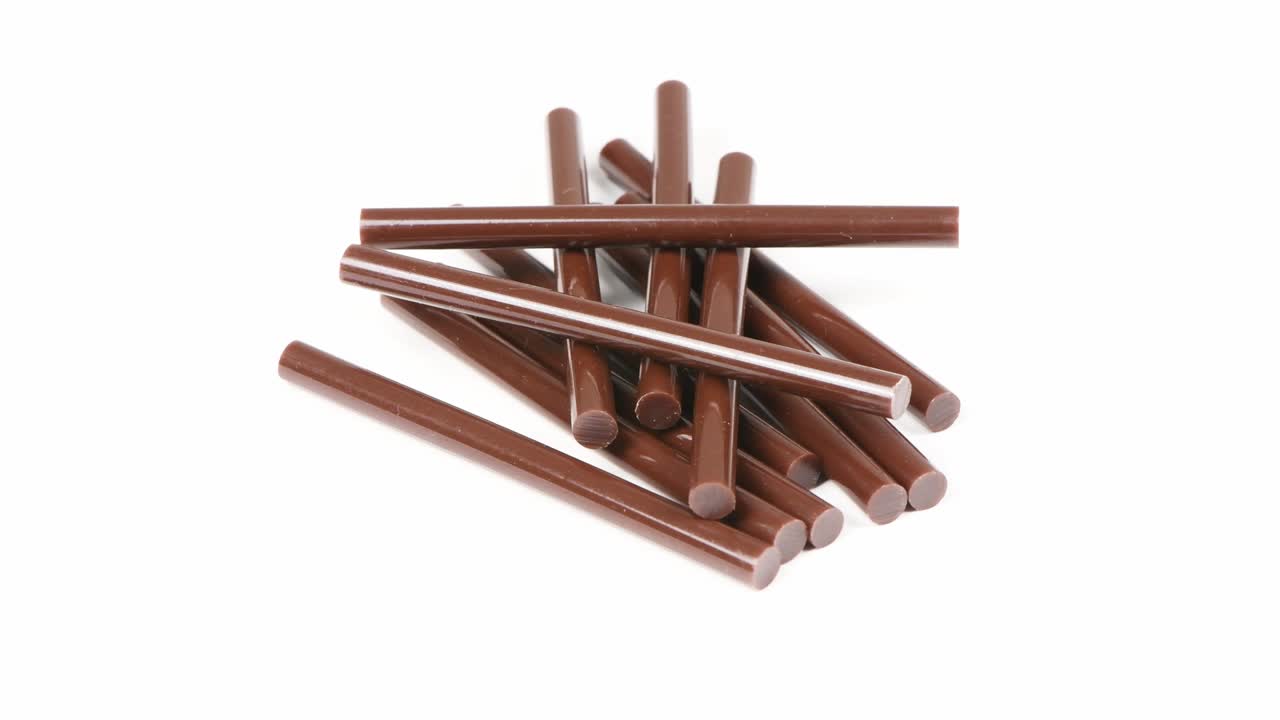 las barras de la pistola de pegamento color marrón primer plano. rotación en sentido contrario a las agujas del reloj. vista lateral. movimiento en bucle. rotación 360.