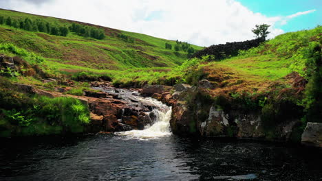 small waterfall running with a stream, in the english lake district, bright sunny day