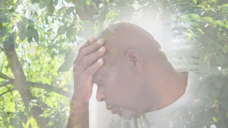 Video composito di uomo anziano afroamericano stressato su sfondo di foglie su alberi alti