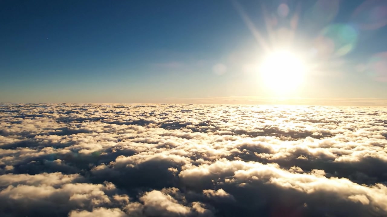 Una vista mozzafiato sopra le nuvole catturata all'alba, che mostra il bagliore dorato del sole che illumina lo strato di nuvole soffici e vaporose sottostante in un cielo sereno