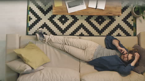 man on couch talking on phone