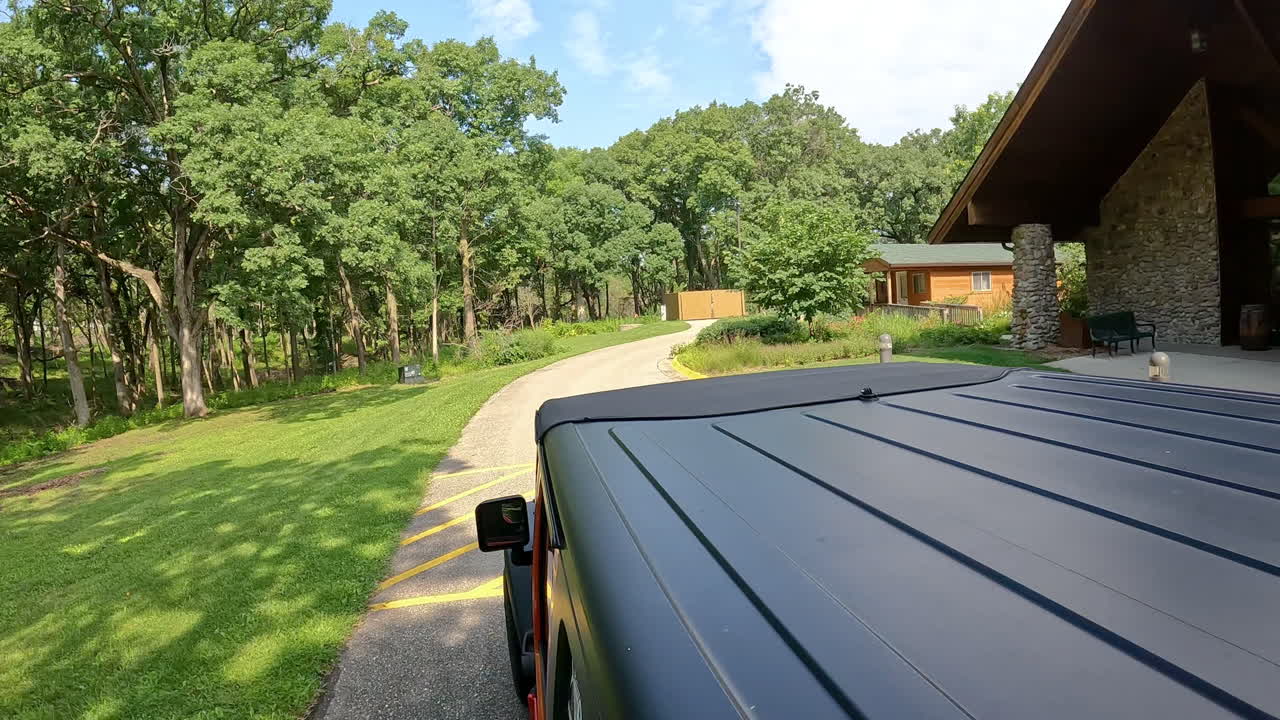 POV from vehicle roof - driving on paved road in a county park past the Jester Park Lodge in central Iowa on a sunny, summer day; vacation, holiday or recreation