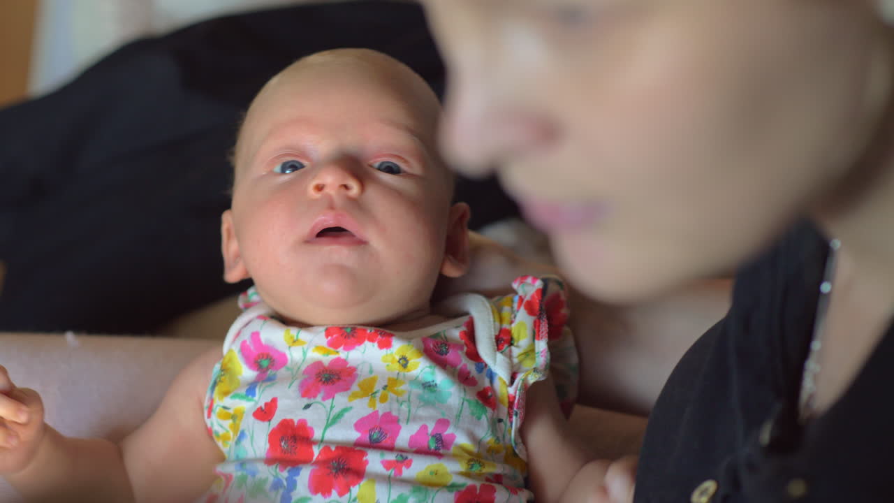 두 달 된 아기 소녀가 어머니의 팔에