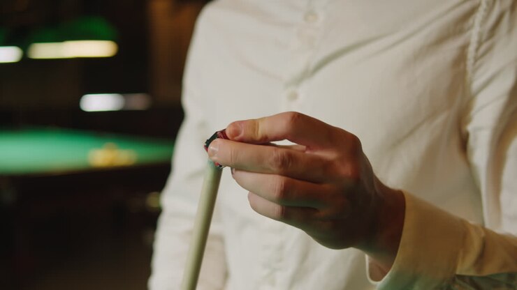 Young billiard player man wearing white shirt preparing a cue for a game close-up. Billiards team sport. High quality 4k footage