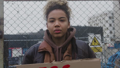 close up view of young american female activist holding a cardboard placard during a climate change protest while looking at camera