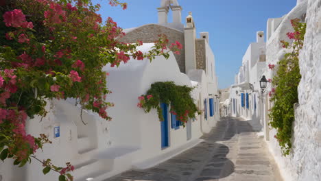 whitewashed street with pink bougainvillea in a greek island village