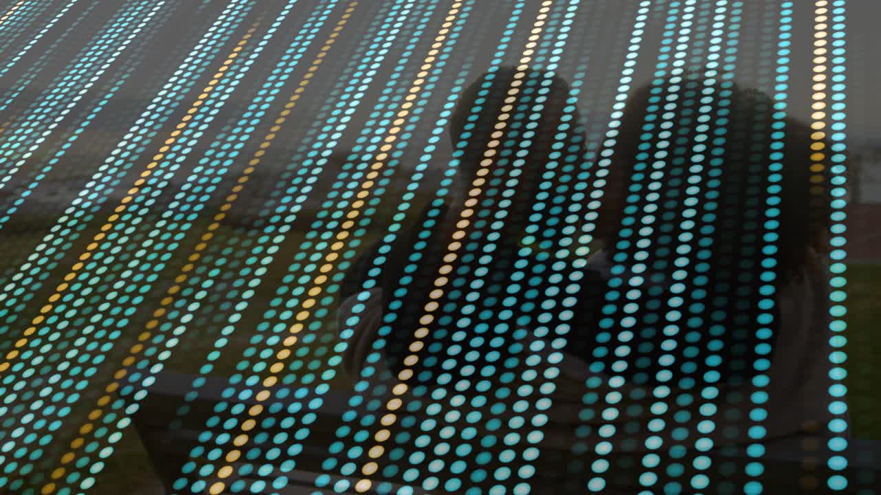 Camera panning revealing friends sharing ideas on bench in technology demo with drifting dot film