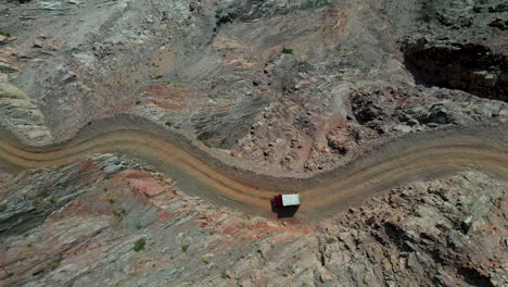 Dramatic-aerial-shot-of-vehicle-on-Fairy-Meadows-Road-in-Pakistan,-second-deadliest-highway-in-the-world,-downward-angle-drone