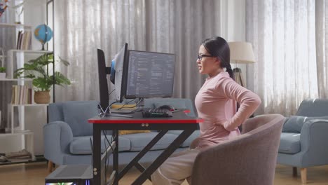 mujer que experimenta dolor de espalda mientras codifica en casa