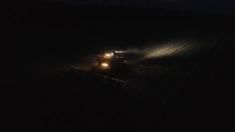 Cosechadora-De-Tractores-Operando-En-Un-Campo-En-La-Vista-Aérea-Nocturna