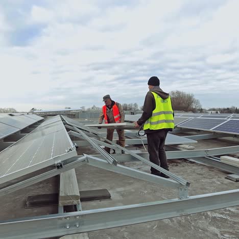 engineers installing new solar panel. workers in protective uniform put sunny battery on the metal basis in the solar farm. alternative source of energy.