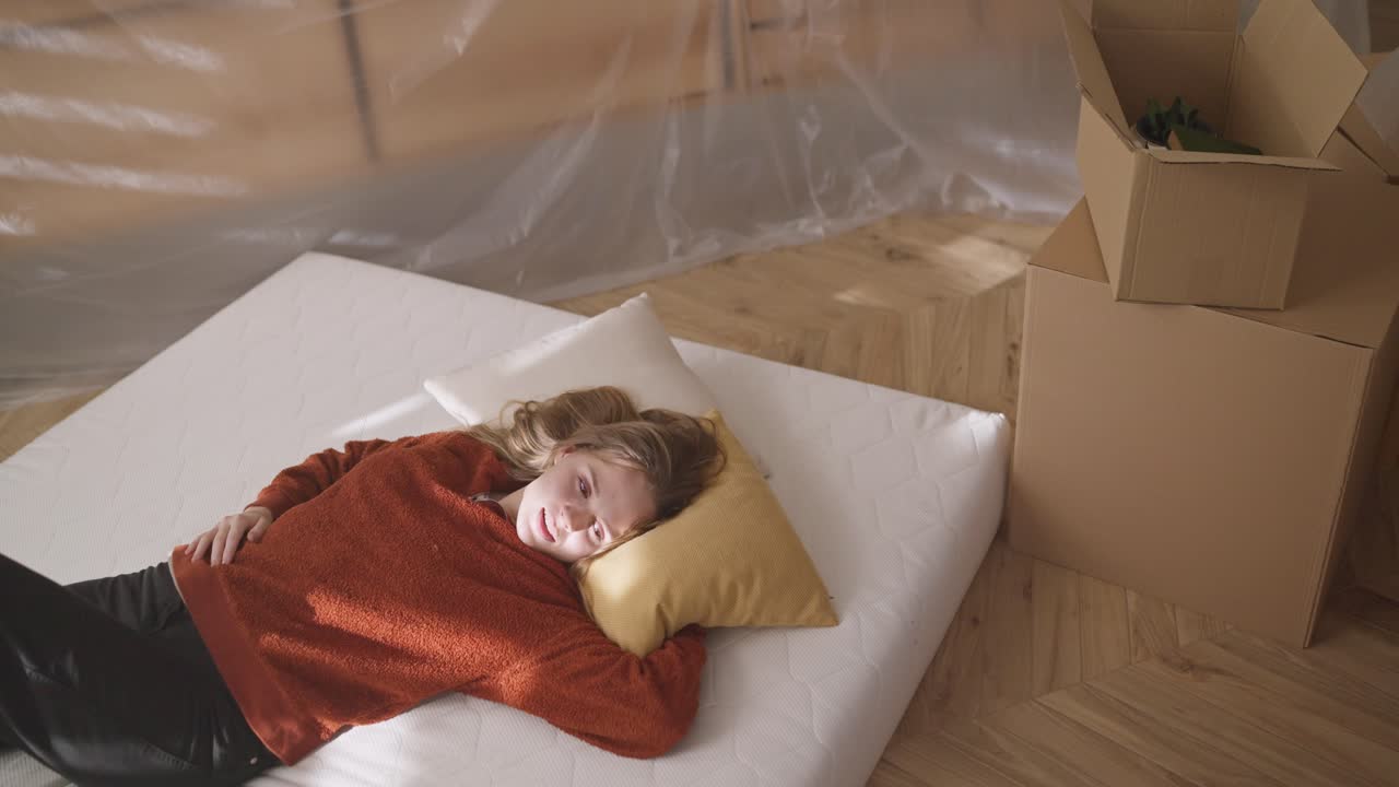 새로운 집 에서 매트리스 에서 휴식을 취 하는 여자