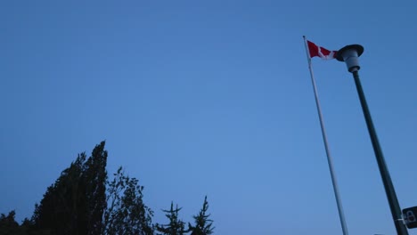 Vista-En-Cámara-Lenta-Paisaje-Zoom-Vista-En-La-Bandera-De-Canadá-Mientras-El-Viento-Sopla-En-El-Cielo-Del-Atardecer