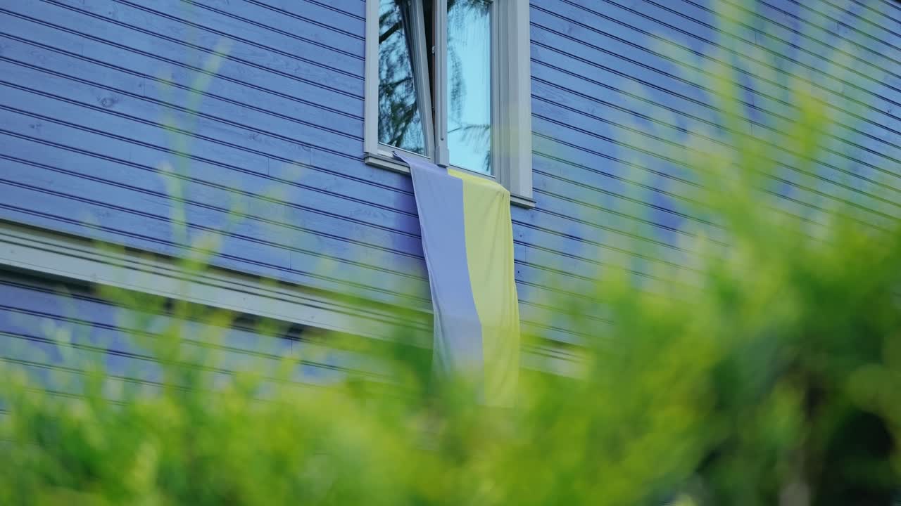 Faded Ukraine flag draped on rural house window showing solidarity in wartime