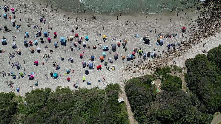Immergiti nella bellezza costiera di Llandudno Beach, Città del Capo, con riprese diurne da drone su vivaci ombrelloni da spiaggia