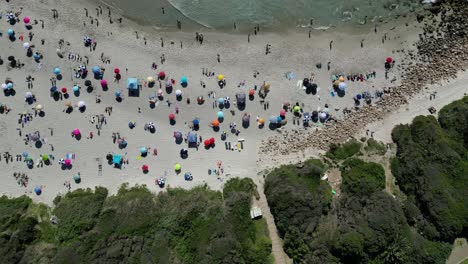 Sumérgete-En-La-Belleza-Costera-De-La-Playa-De-Llandudno,-En-Ciudad-Del-Cabo,-Con-Imágenes-Diurnas-De-Drones-Sobre-Vibrantes-Sombrillas-De-Playa.