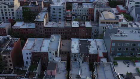 aerial footage slights sideways across brownstone rooftops of harlem, nyc, at golden hour sunrise