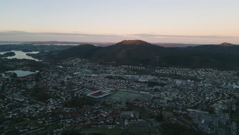 Bergen,-Norwegen-In-Der-Abenddämmerung-Mit-Den-Lichtern-Der-Stadt-Und-Den-Umliegenden-Hügeln,-Luftaufnahme