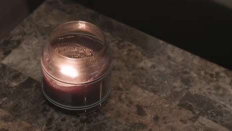 still shot of a scented candle burning on a modern granite tabletop