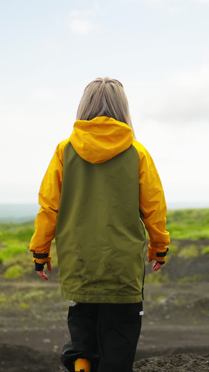 Woman in Yellow Jacket Walking Through a Vast Outdoor Landscape
