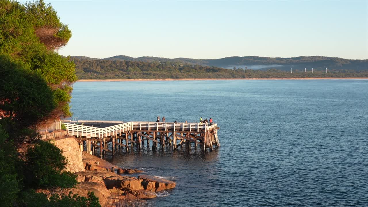 Early morning fishermen on Tathra wharf, New South Wales, Australia. Wide shot