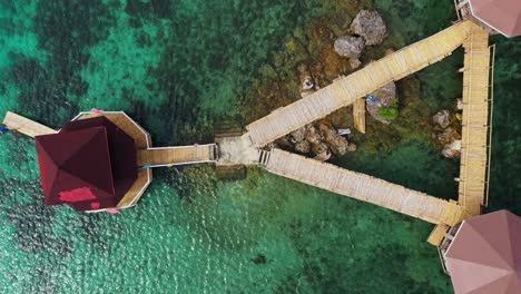 Boardwalk-On-Rocky-Outcrop-With-Wooden-Gazebos-Built-In-Shallow-Blue-Sea