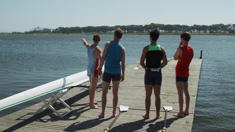 Rear-view-of-male-rower-team-discussing-on-the-jetty