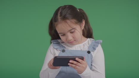 retrato de estudio de una joven en el espectro asd jugando con un teléfono móvil en un fondo verde 2