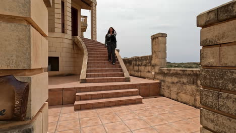 Woman-going-down-some-large-terracotta-stairs-in-a-luxurious-house