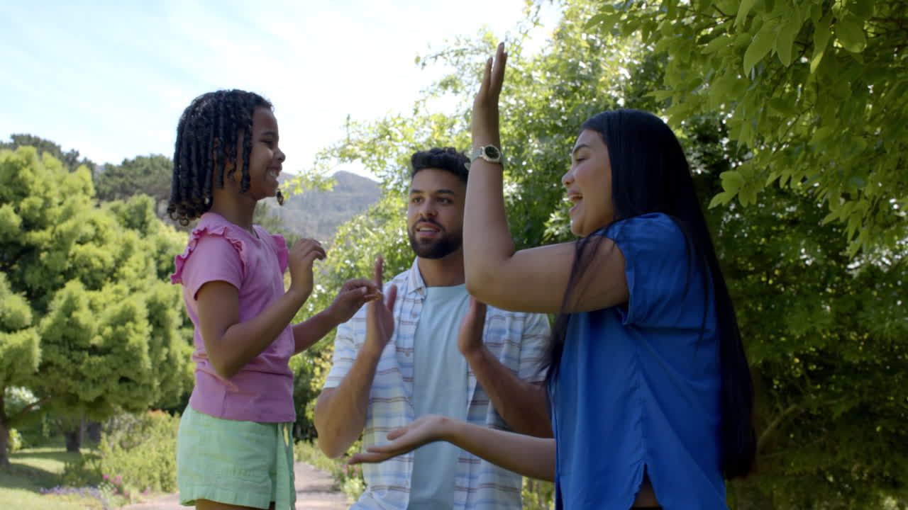 Family enjoying playful clapping game outdoors, smiling and bonding together