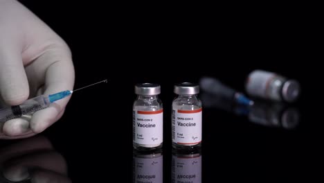 botellas de vacuna covid-19 y la mano sostiene una jeringa llena que trata la pandemia de coronavirus